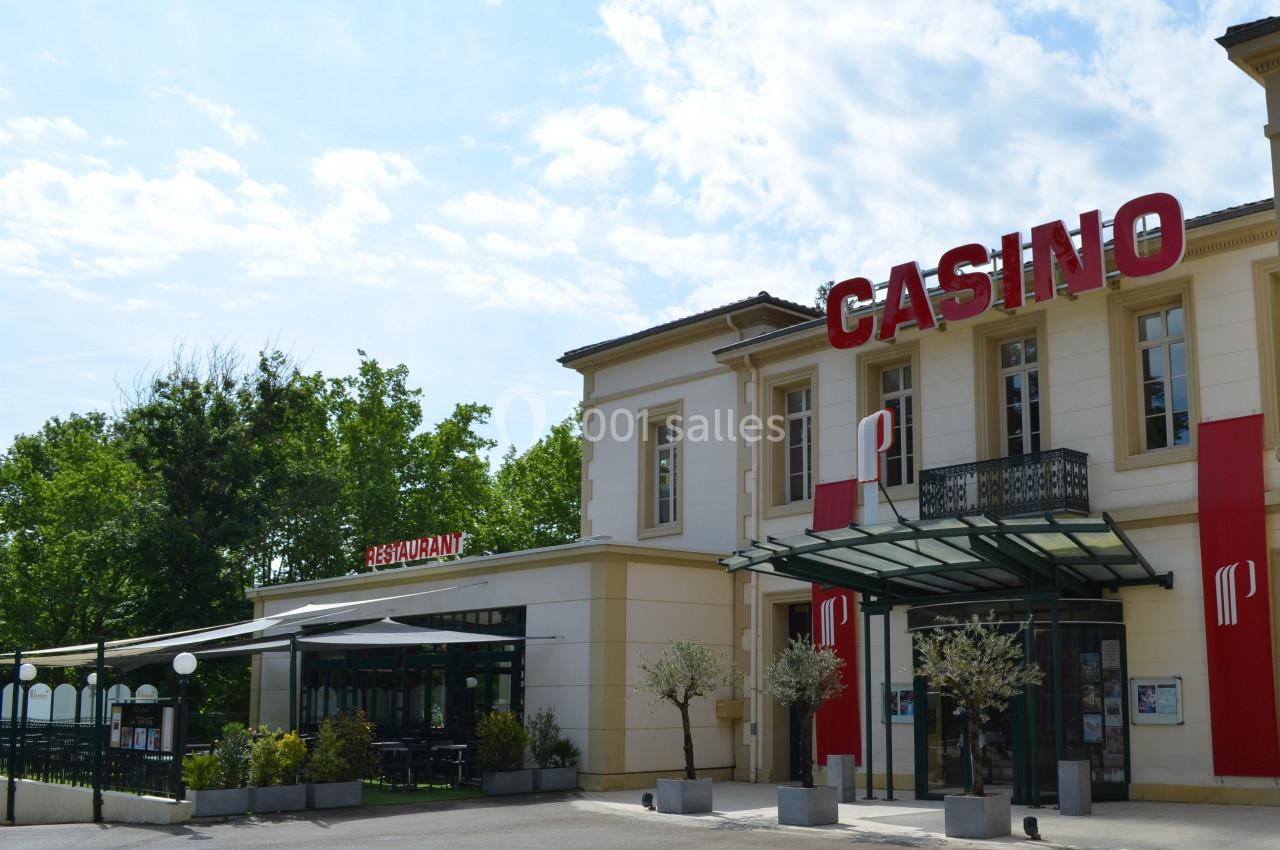 Façade d'un bâtiment abritant un casino et un restaurant, entouré d'arbres et d'une terrasse extérieure.