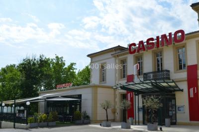 Main empilant des jetons de casino colorés sur une table, avec un arrière-plan flou de lumières et de jeux.