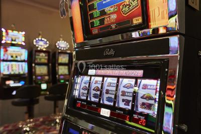 Main empilant des jetons de casino colorés sur une table, avec un arrière-plan flou de lumières et de jeux.