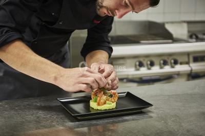 Main empilant des jetons de casino colorés sur une table, avec un arrière-plan flou de lumières et de jeux.