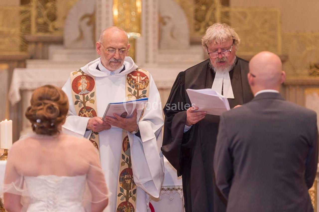 Deux officiants religieux dirigent une cérémonie de mariage devant un couple dans une église.