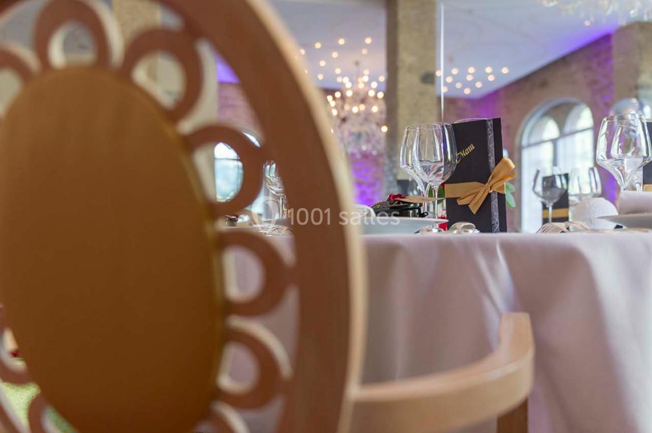 Vue rapprochée d'une chaise décorative et d'une table dressée avec des verres, un menu et une ambiance lumineuse élégante.