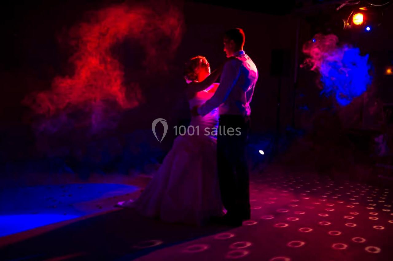 Un couple danse sous des lumières colorées dans une ambiance tamisée.
