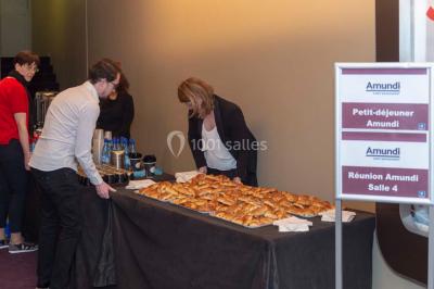 Un groupe de personnes en tenue formelle pose sur une scène lors d'un événement avec un écran affichant des logos en arrière…