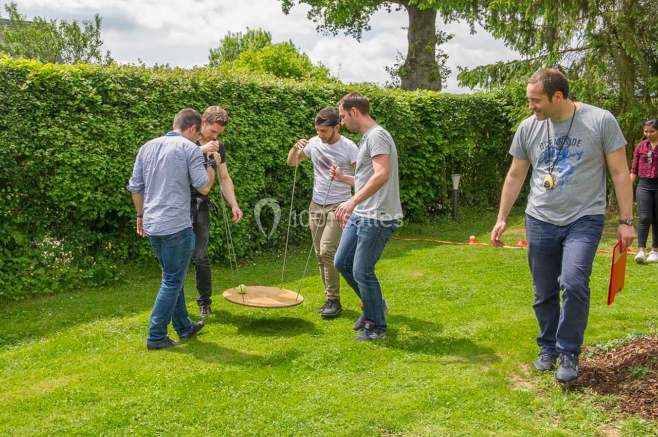 Un groupe de personnes coopère pour déplacer une plateforme suspendue dans un jardin verdoyant.
