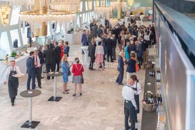 Un groupe de personnes en tenue formelle pose sur une scène lors d'un événement avec un écran affichant des logos en arrière…