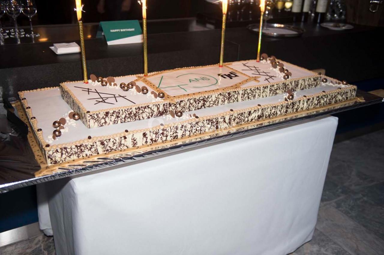 Gâteau rectangulaire décoré de chocolat et bougies allumées, posé sur une table recouverte d'une nappe blanche.