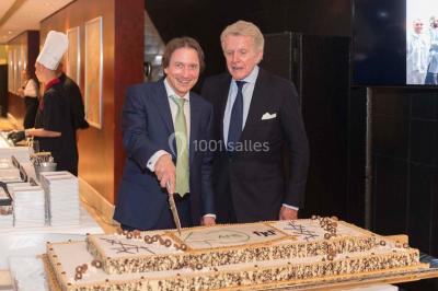 Un groupe de personnes en tenue formelle pose sur une scène lors d'un événement avec un écran affichant des logos en arrière…