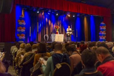Un groupe de personnes en tenue formelle pose sur une scène lors d'un événement avec un écran affichant des logos en arrière…