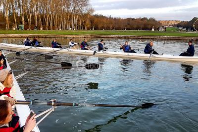Un groupe de personnes souriantes pose dans une salle avec des rameurs et un écran projeté en arrière-plan.