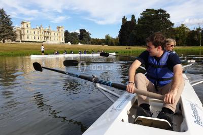 Un groupe de personnes souriantes pose dans une salle avec des rameurs et un écran projeté en arrière-plan.