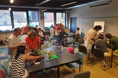 Un groupe de personnes souriantes pose dans une salle avec des rameurs et un écran projeté en arrière-plan.