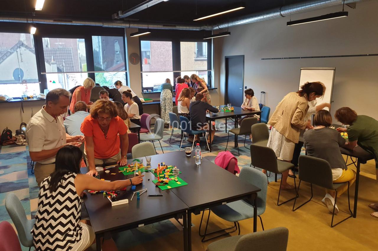 Des personnes participent à un atelier collaboratif autour de tables, utilisant des blocs de construction colorés.