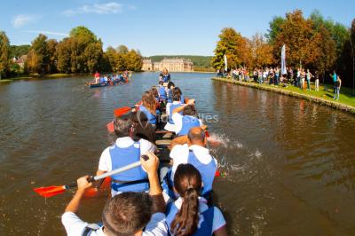 Un groupe de personnes souriantes pose dans une salle avec des rameurs et un écran projeté en arrière-plan.