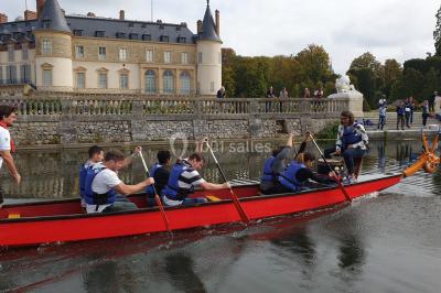 Un groupe de personnes souriantes pose dans une salle avec des rameurs et un écran projeté en arrière-plan.