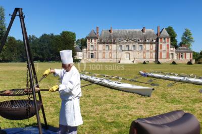 Un groupe de personnes souriantes pose dans une salle avec des rameurs et un écran projeté en arrière-plan.