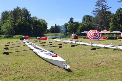 Un groupe de personnes souriantes pose dans une salle avec des rameurs et un écran projeté en arrière-plan.