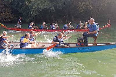 Un groupe de personnes souriantes pose dans une salle avec des rameurs et un écran projeté en arrière-plan.