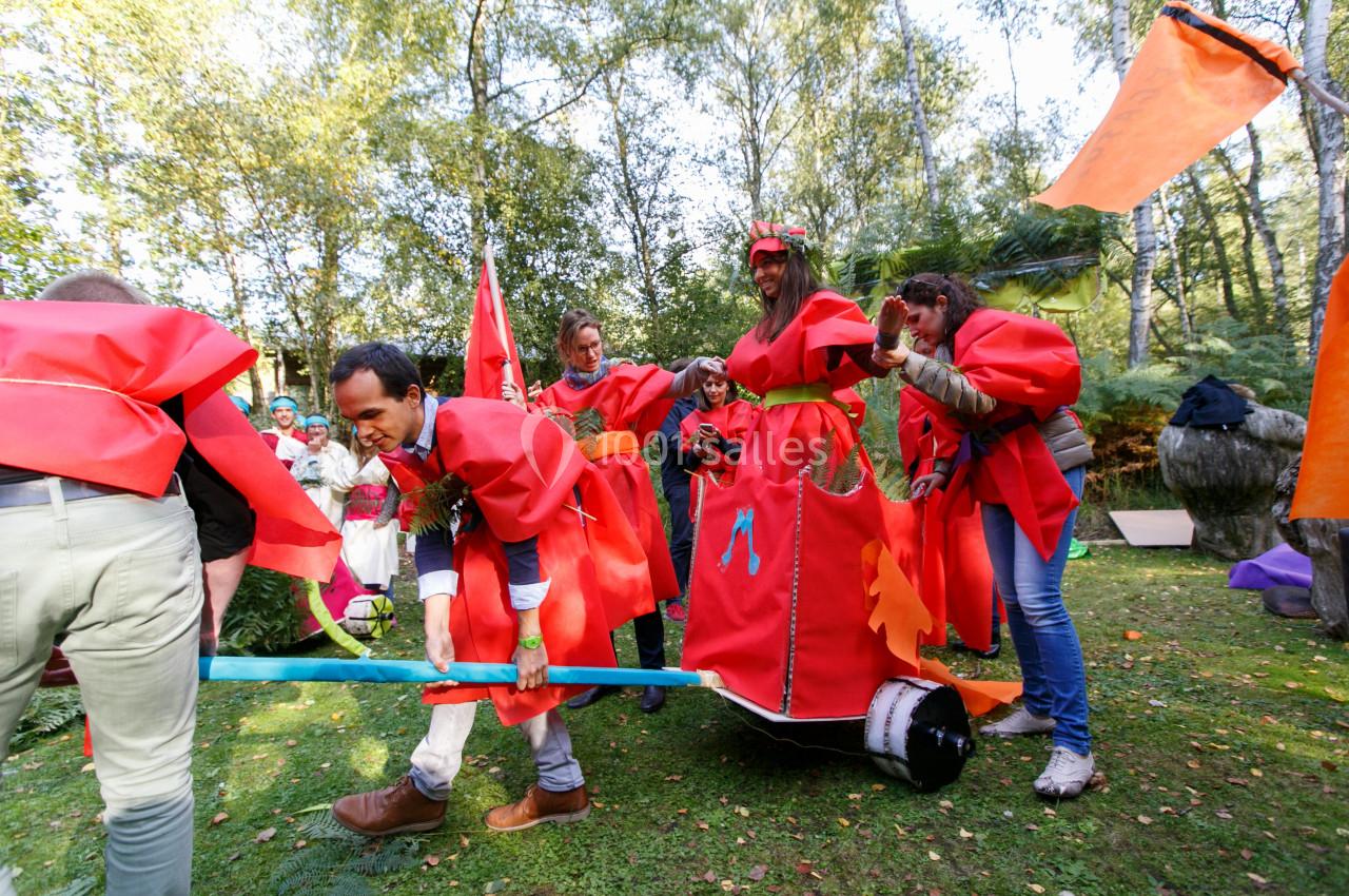 Des personnes déguisées en costumes rouges participent à une activité ludique en plein air dans un cadre boisé.