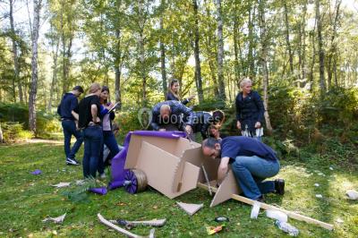 Un groupe de personnes souriantes pose dans une salle avec des rameurs et un écran projeté en arrière-plan.