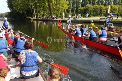 Un groupe de personnes souriantes pose dans une salle avec des rameurs et un écran projeté en arrière-plan.
