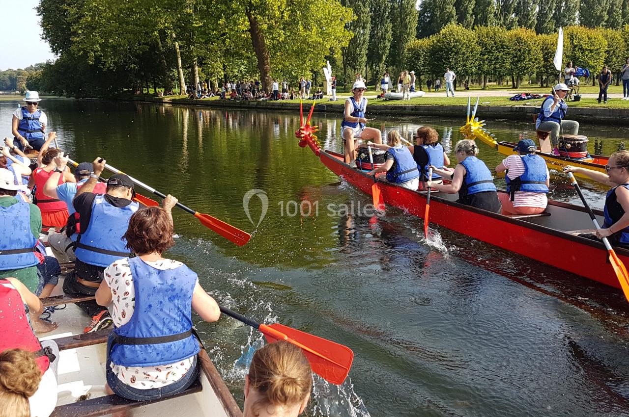 Des équipes pagaient sur des bateaux-dragons colorés lors d'une course sur une rivière bordée d'arbres.