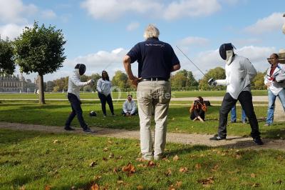 Un groupe de personnes souriantes pose dans une salle avec des rameurs et un écran projeté en arrière-plan.