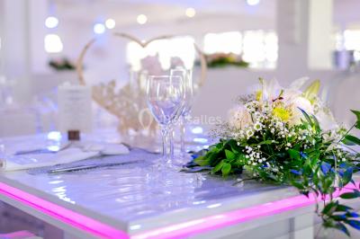 Table décorée avec des fleurs blanches, des ornements royaux ’Queen’ et ’King’, et un fond scintillant.
