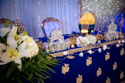 Table décorée avec des fleurs blanches, des ornements royaux ’Queen’ et ’King’, et un fond scintillant.