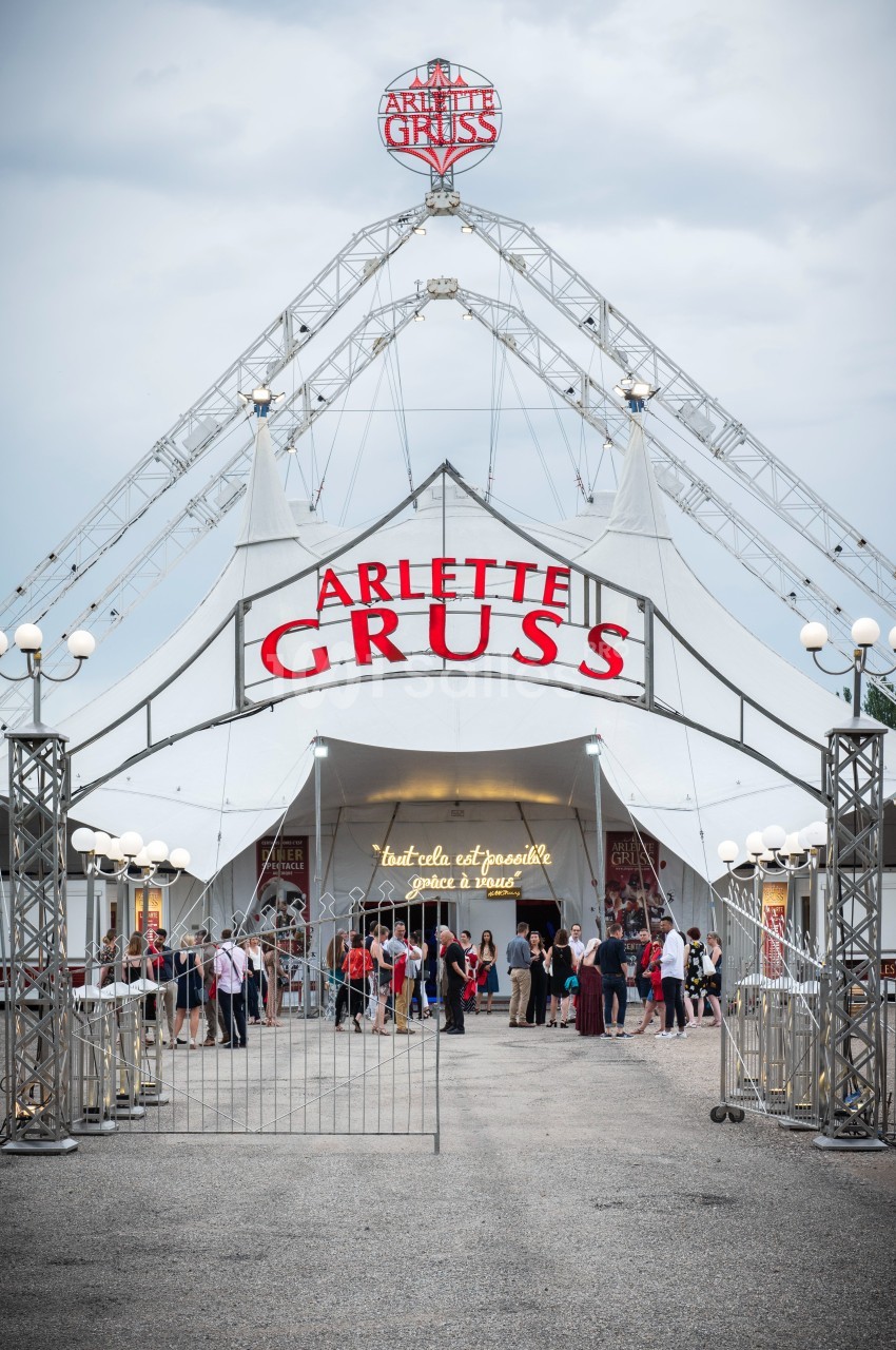 Entrée principale d'un chapiteau de cirque blanc avec l'inscription ’Arlette Gruss’, des visiteurs devant.