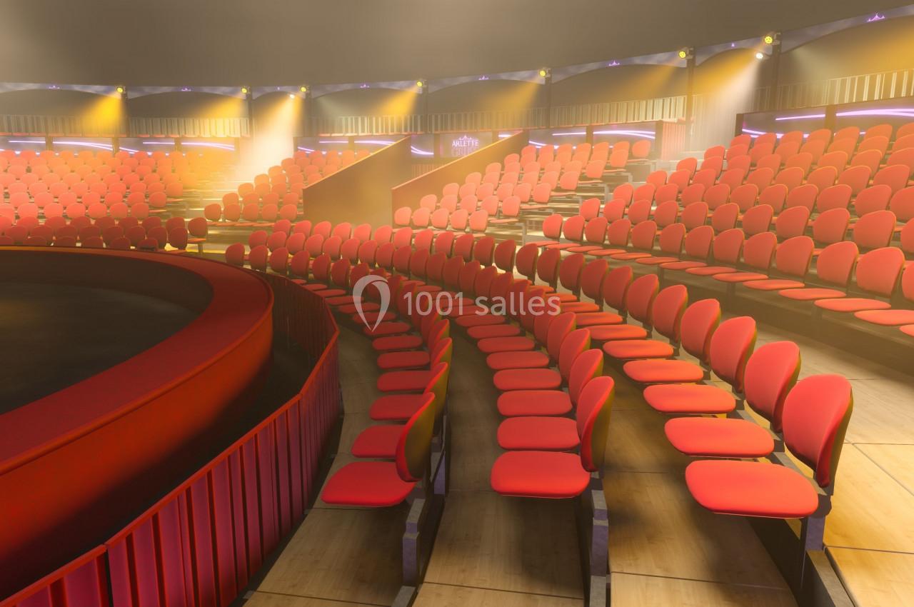 Gradins circulaires avec des sièges rouges vides, éclairés par une lumière douce dans un espace intérieur.