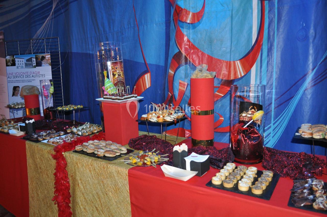 Buffet décoré avec des plats variés, des desserts et des décorations rouges et dorées sur une nappe festive.