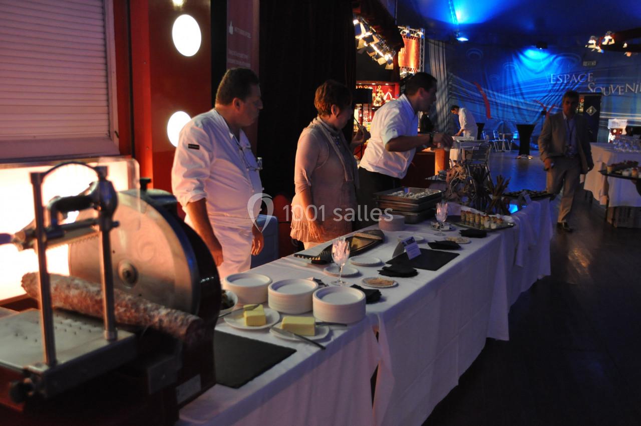 Des chefs préparent un buffet avec des plats variés sur une table dans une salle éclairée.