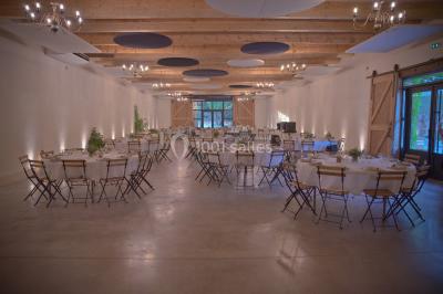 Façade d'une grande maison blanche entourée d'arbres, avec une pelouse verdoyante au premier plan.