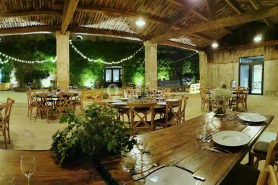 Façade d'une grande maison blanche entourée d'arbres, avec une pelouse verdoyante au premier plan.