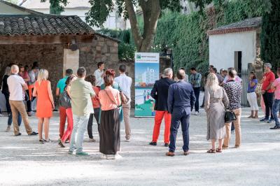Façade d'une grande maison blanche entourée d'arbres, avec une pelouse verdoyante au premier plan.