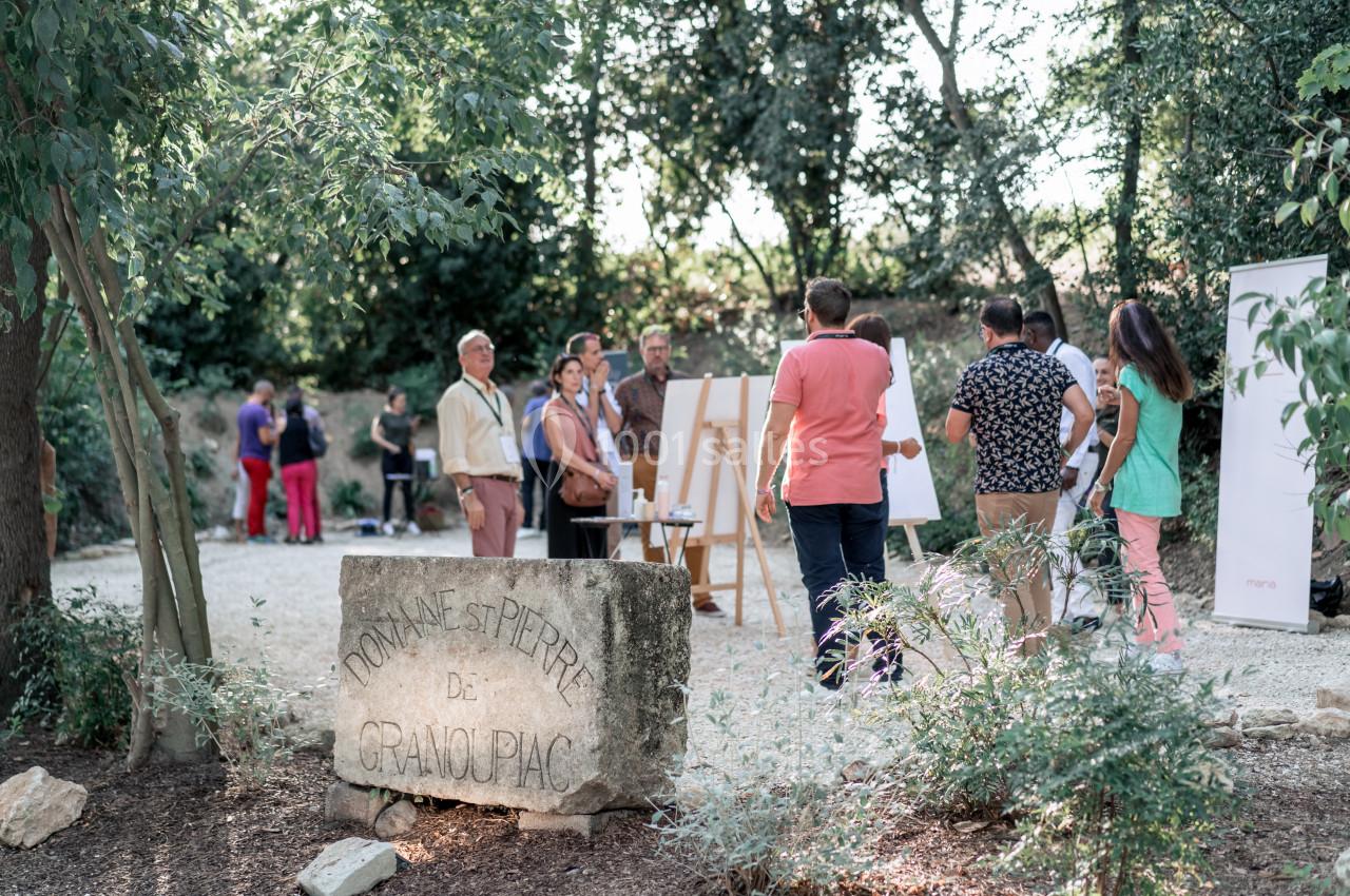 Un groupe de personnes participe à une activité en plein air dans un espace boisé, près d'une pierre gravée.