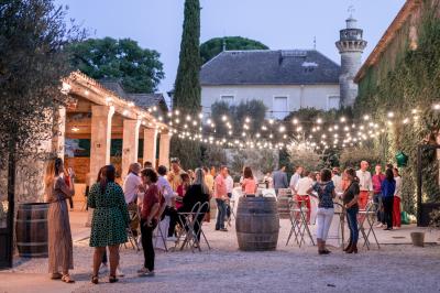 Façade d'une grande maison blanche entourée d'arbres, avec une pelouse verdoyante au premier plan.