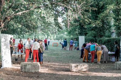 Façade d'une grande maison blanche entourée d'arbres, avec une pelouse verdoyante au premier plan.