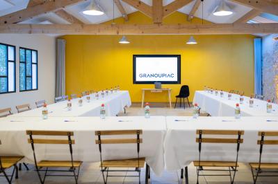 Façade d'une grande maison blanche entourée d'arbres, avec une pelouse verdoyante au premier plan.