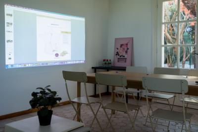 Façade d'une grande maison blanche entourée d'arbres, avec une pelouse verdoyante au premier plan.