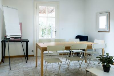 Façade d'une grande maison blanche entourée d'arbres, avec une pelouse verdoyante au premier plan.