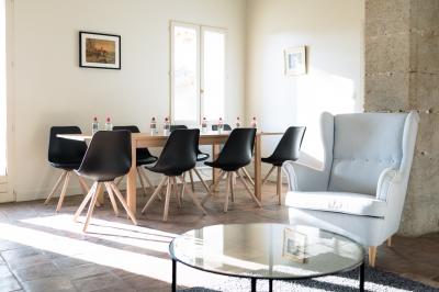 Façade d'une grande maison blanche entourée d'arbres, avec une pelouse verdoyante au premier plan.