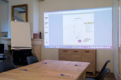 Façade d'une grande maison blanche entourée d'arbres, avec une pelouse verdoyante au premier plan.