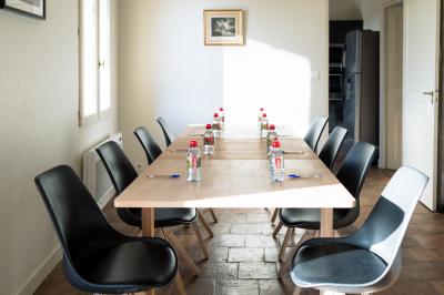 Façade d'une grande maison blanche entourée d'arbres, avec une pelouse verdoyante au premier plan.