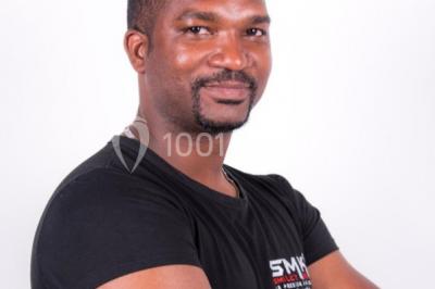 Salle de réception avec tables dressées, nappes blanches, chaises décorées et éclairage naturel à travers de grandes…
