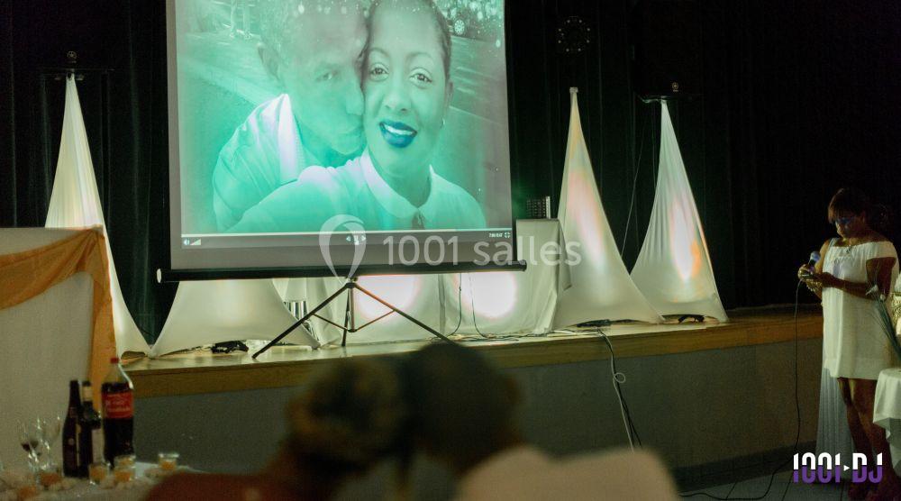 Projection d'une photo de couple sur un écran lors d'un événement dans une salle décorée avec des lumières tamisées.
