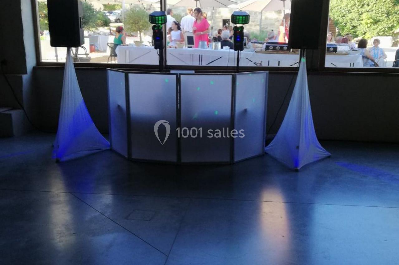 Console de DJ installée en extérieur, entourée de rideaux blancs et éclairée par la lumière naturelle.