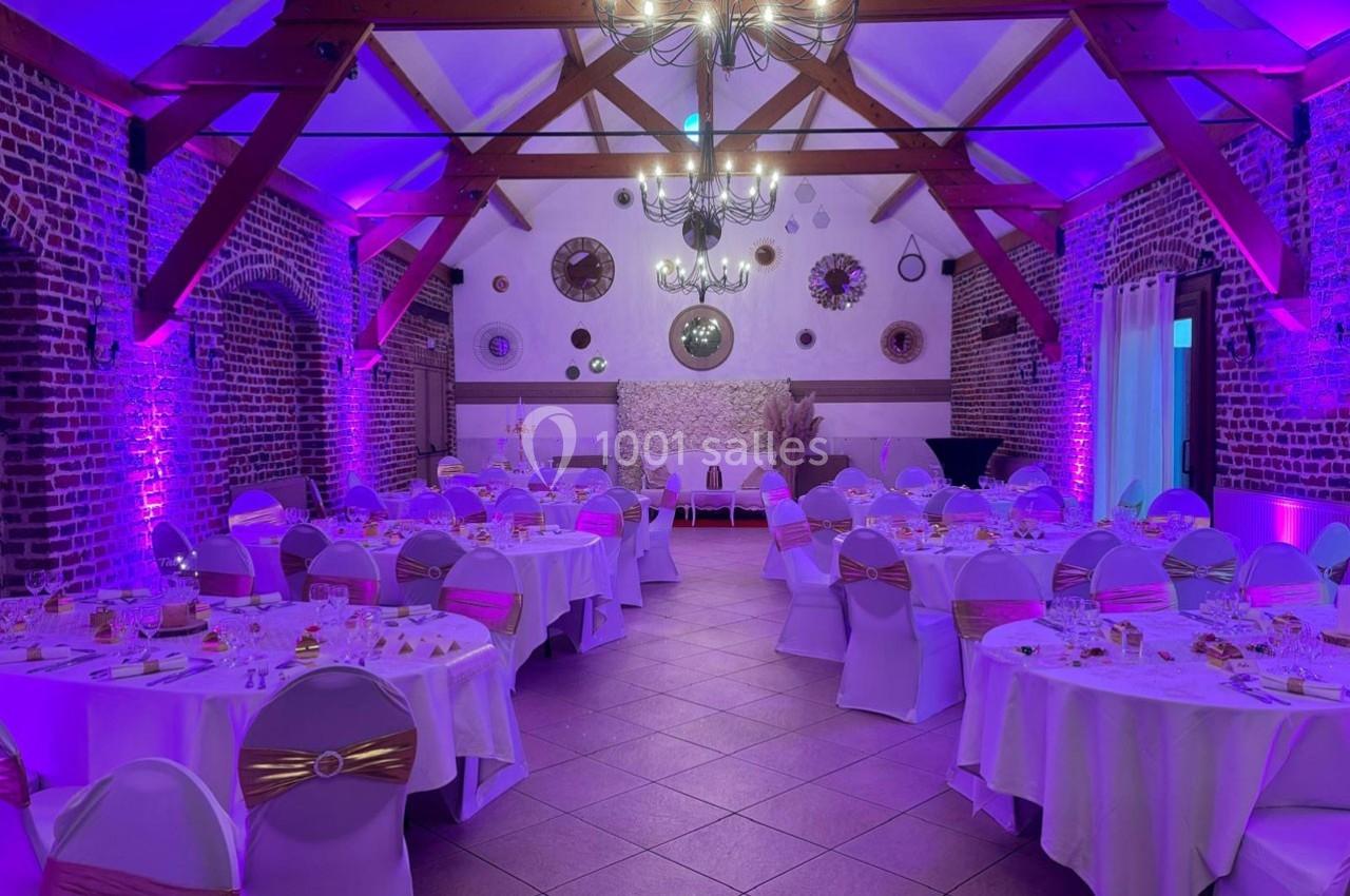 Traiteur Forest-sur-Marque (Nord) - Auberge du Tilleul #10 Salle de réception décorée avec des tables rondes dressées, éclairage violet et poutres apparentes au plafond.