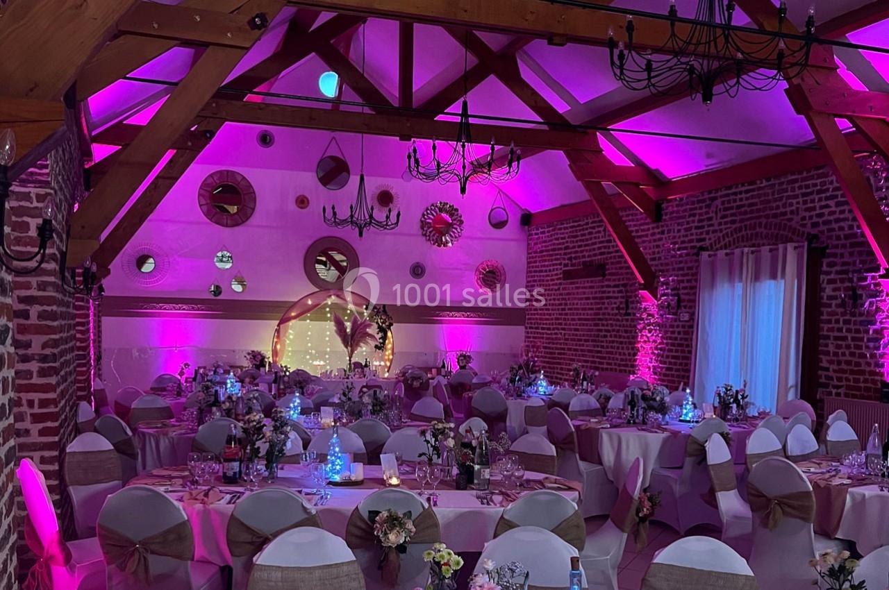 Traiteur Forest-sur-Marque (Nord) - Auberge du Tilleul #16 Salle de réception décorée avec des tables rondes, des chaises habillées et un éclairage rose chaleureux.